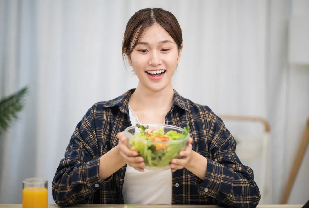 笑顔でサラダを食べる女性